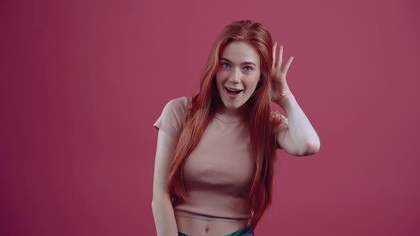 Cute Young Redhead of 20 Years in a Pink Casual Tshirt Isolated on a Pink Background