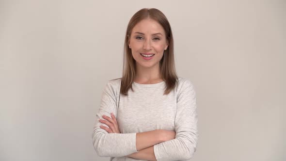 Portrait of happy woman standing with crossed hands and smiling. indoor studio shot