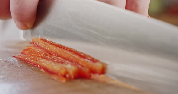 Extreme macro of a chef knife slicing a red bell pepper