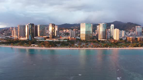 Wide rising aerial dolly shot of run reflections off buildings in Honolulu on the island of O'ahu, H