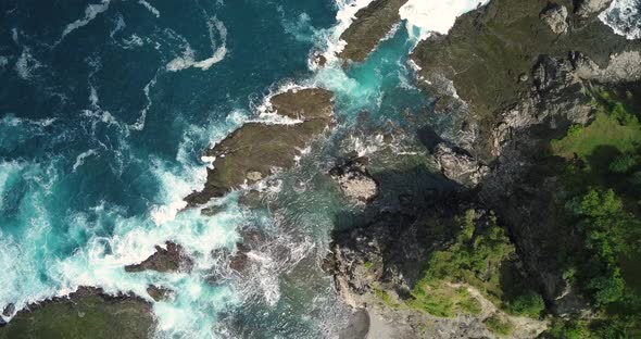 Sliding overhead shot of waves of Indian Ocean hitting boulder and coral reef in the beach in sunny