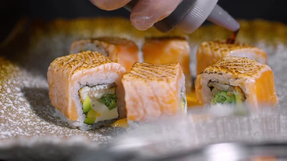 Cook Pouring Sauce of Sushi Rolls