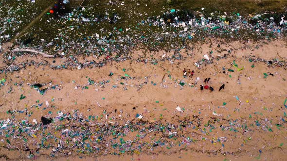 Aerial top view of children playing on the beach completely full of plastic bags. The sadness of civ