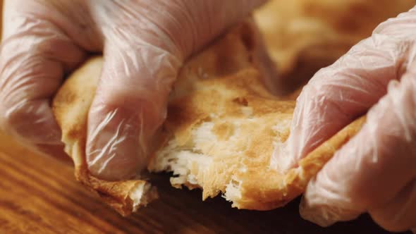 Woman's hands tearing bread from a tandoor