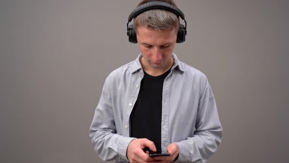 Young Adult Focused on Using a Smartphone Whilst Wearing Headphones