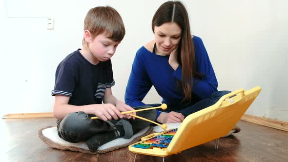 Boy Plays the Xylophone for His Mother Sitting on the Floor.