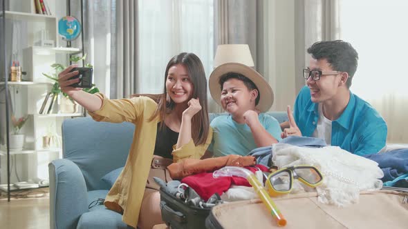 Happy Asian Family Packing Clothes In A Suitcase And Selfie For A New Journey