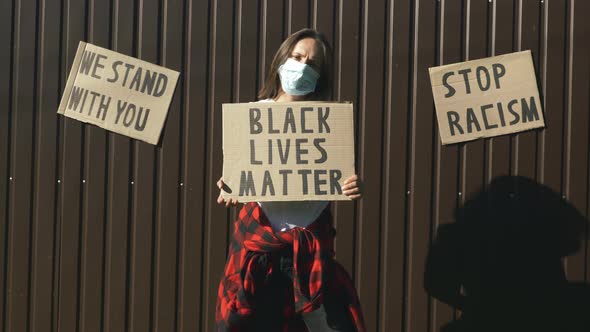 Caucasian woman in protective face mask with poster "Black lives matter"