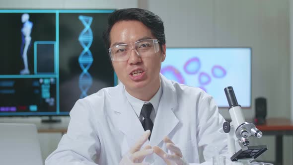 Asian Scientist In The Laboratory With A Microscope And Speaking To The Camera