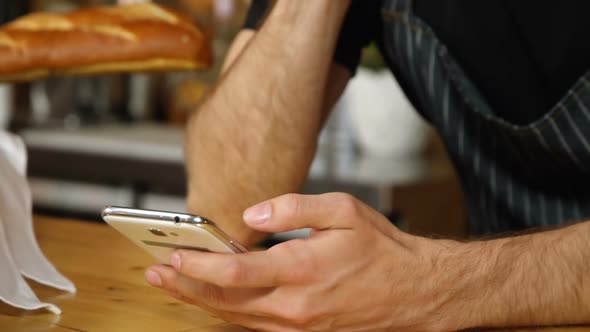 Waiter using mobile phone at counter