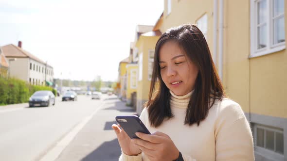 Close up of a Asian woman happy face standing and using her smartphone