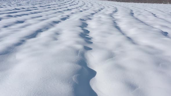 Above the snow zastrugi on the ground 4K drone video