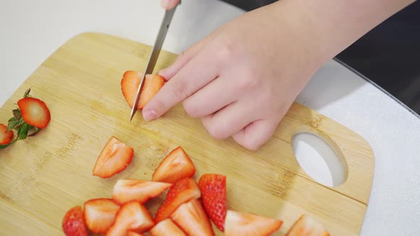 Strawberries are Cut Into Pieces on a Wooden Cutting Board to Decorate Desserts