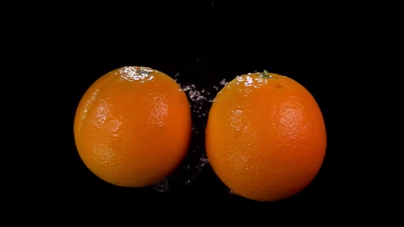 Two Fresh Oranges Are Flying and Colliding with Each Other Rising Drops of Water