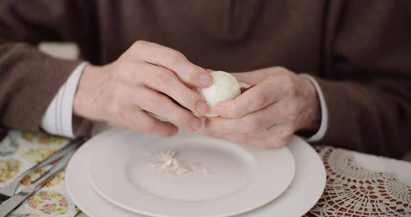 Old Man Peeling Egg on Plate