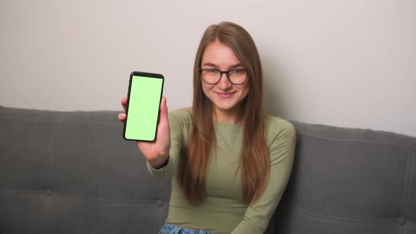 Pretty Smiling Caucasian Businesswoman in Glasses Showing Smartphone with Green Screen Chromakey