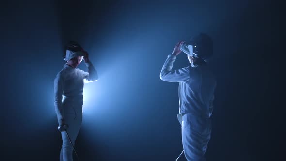 Two Young Female Fencers Take Off Their Fencing Masks Salute with Rapiers and Greet Each Other