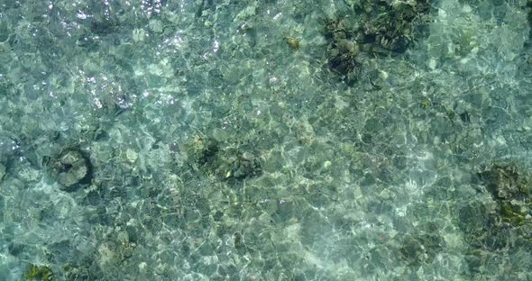 Wide fly over travel shot of a paradise sunny white sand beach and aqua blue water background in 4K