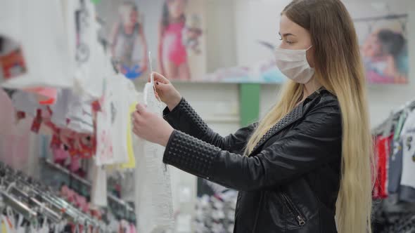 Young Mother in Medical Mask Buying Tshirt for Child in Supermarket