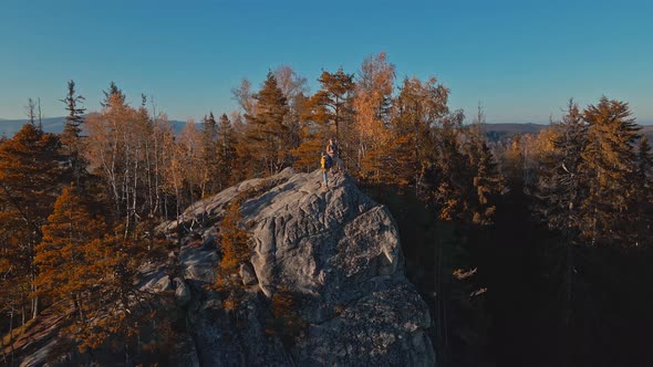 Cinematic Aerial Footage From Drone Flying Over Couple Hikers Standing on Top of Cliff in Woody