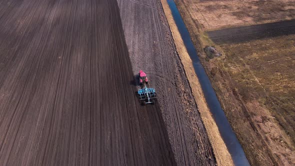 Tractor Plows Ground on Cultivated Farm Field