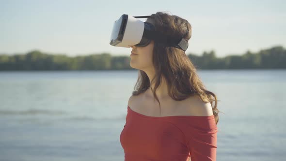 Portrait of Young Brunette Woman in VR-glasses Looking Around with Excited Surprised Facial