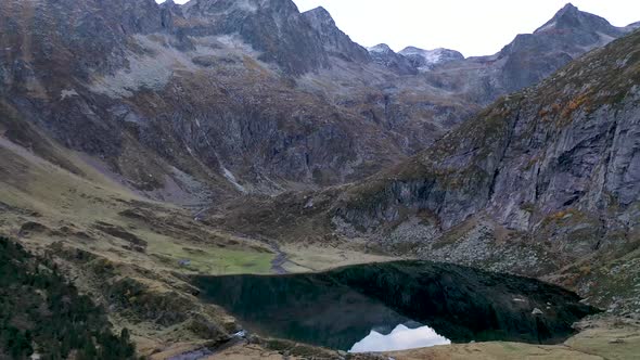 Lac d'Espingo mountain lake with calm water located in Haute-Garonne, Pyrénées, France, Aerial slow