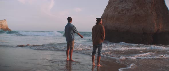 Two friends enjoying the sunset and the ocean on a wild beach