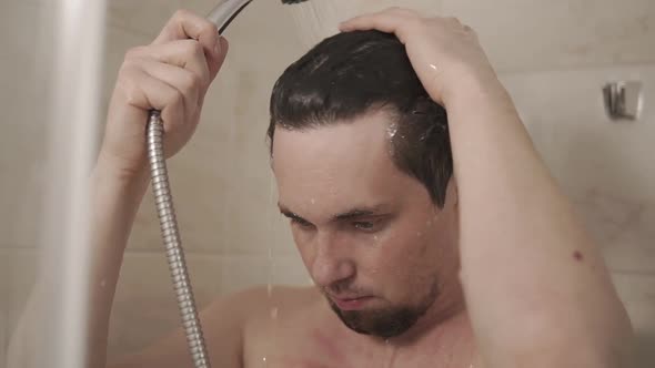 Portrait of a Young Man Who Is Washing in the Shower Under a Mixer