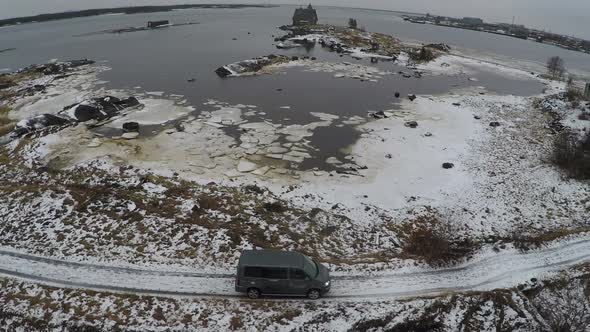 Flying over car driving by the waterside in winter