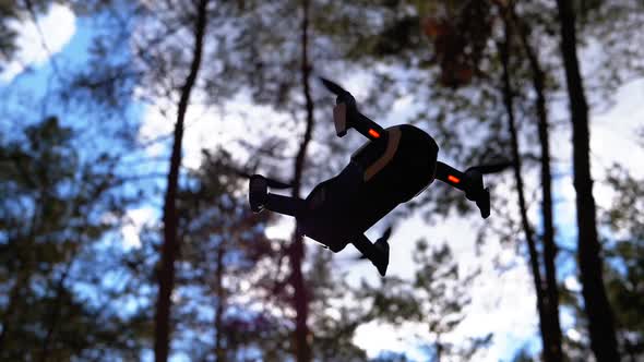 Silhouette of Drone with Camera Hovers in Air on Backdrop of Sunset. Slow Motion