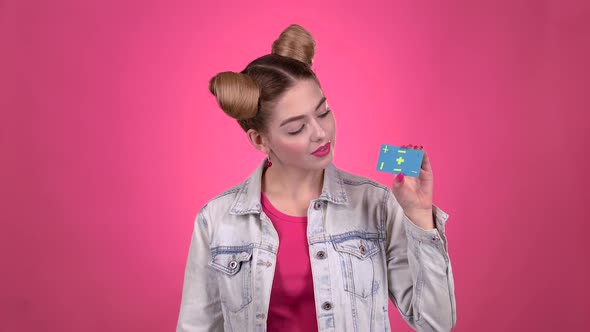 Teenager Advertises a Card and Shows a Thumbs Up. Pink Background. Slow Motion