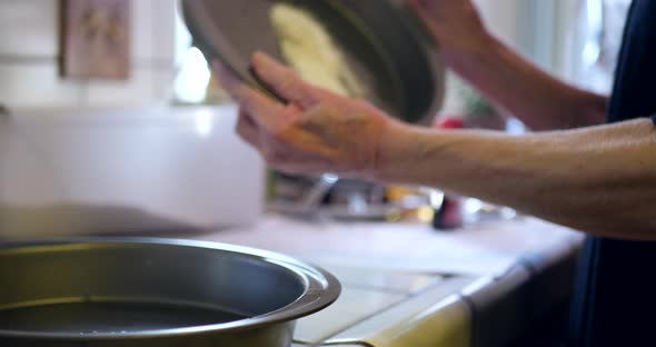 A chef coating round baking pans with flour to work as a non stick surface as she bakes vegan chocol
