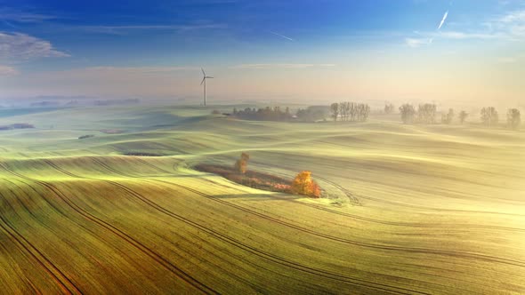 Stunning foggy green field and wind turbine at sunrise, Poland