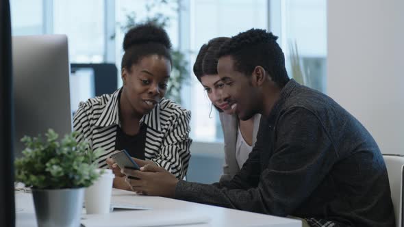 Man Watching Video on Smartphone with Female Colleagues