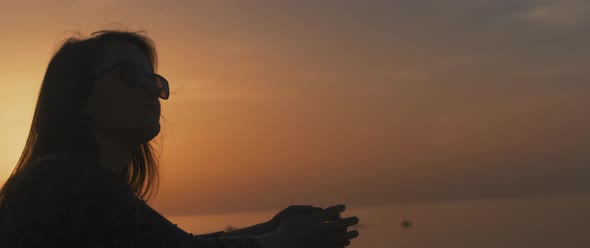 Woman leans on the stone wall at sunset