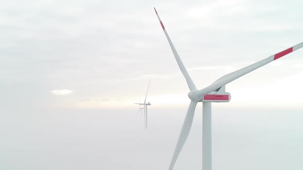 Aerial shot of windmill turbines above a layer of dense mist, producing green, clean energy CROPPED.