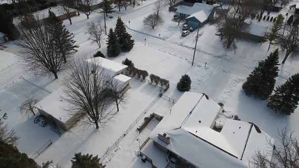 A snowy winter aerial flyover of a typical Michigan residential neighborhood. Snow covers the houses