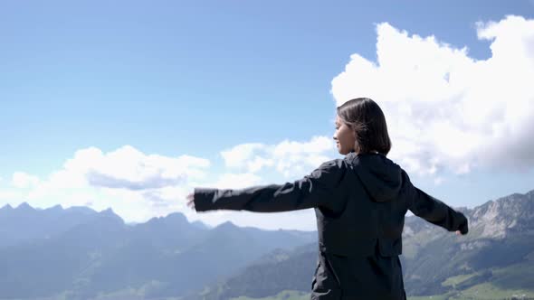 Pretty woman reached peak of mountain and raising arms up in the air in beautiful mountains of Switz