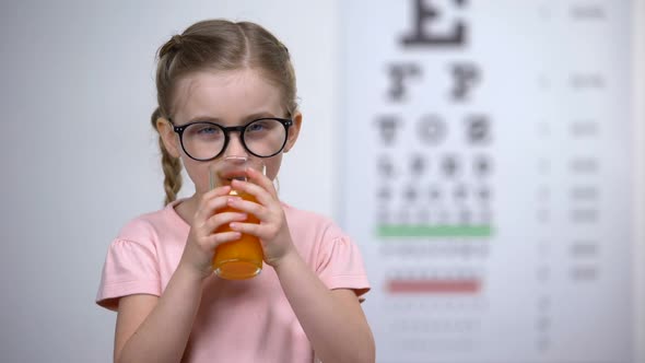 Positive Little Girl Drinking Carrot Smoothie