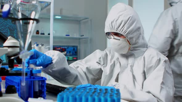 Researcher in Coverall Testing Liquid Sample Using Test Tubes