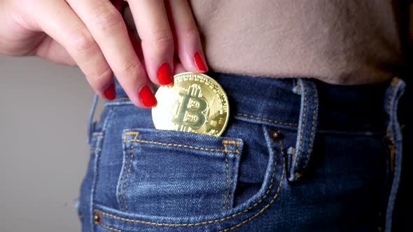 Close up shot of a woman putting a Bitcoin into her pocket.