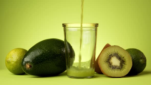 Green Fruit Juice Pouring Into a Glass on a Minimalist Background