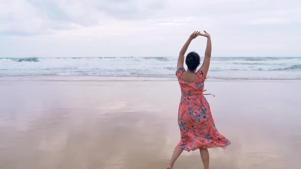 Young Asian woman admiring the beauty of the ocean and stretching her body breathing fresh air.