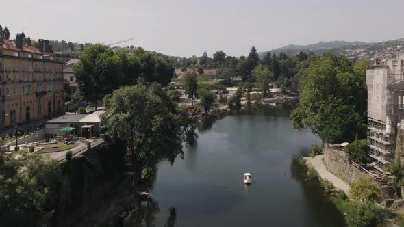 Majestic old medieval stone bridge over river water in Amarante town, aerial fly backward view