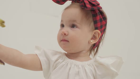 Little girl in plaid headband got a peeled banana