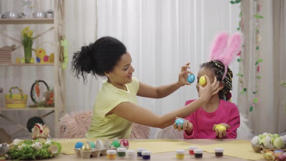 Mom and Daughter with Funny Bunny Ears Laugh and Have Fun with Colored Eggs