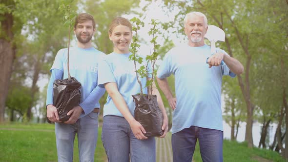 Smiling Eco Activists Holding Tree Saplings and Shovel in Hands, Reforestation