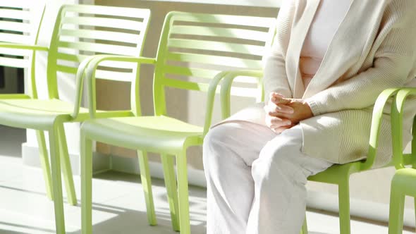 Thoughtful senior woman sitting on chair in lobby