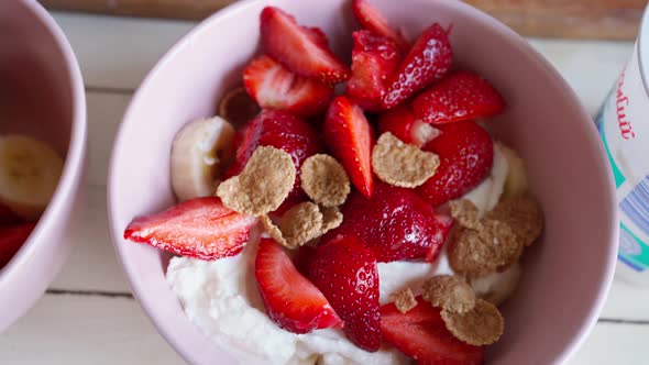 Close Up Putting Flakes in to Bowl with Cutted Strawberry